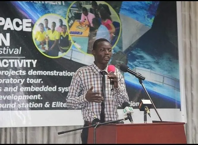 Kenneth speaking at a microphone in front of a space science festival banner