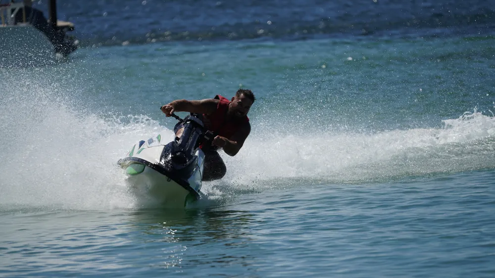 A rider on a jet ski throwing up spray close to shore