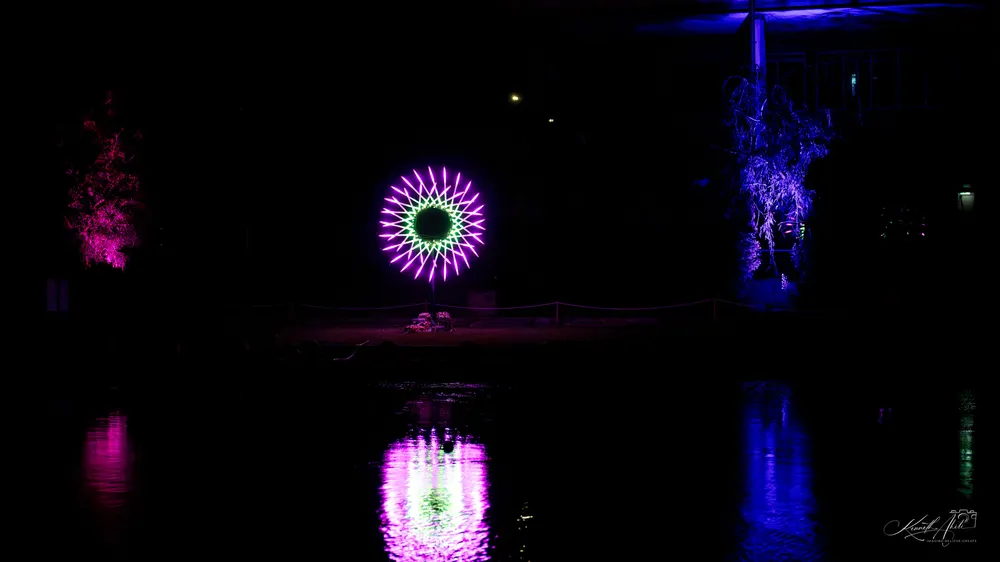 Pink and purple light installations reflected in still water at night