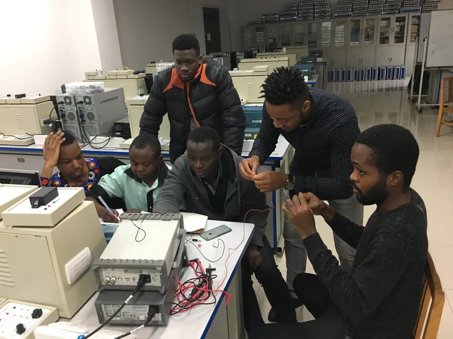 Kenneth and classmates gathered around lab benches with test equipment